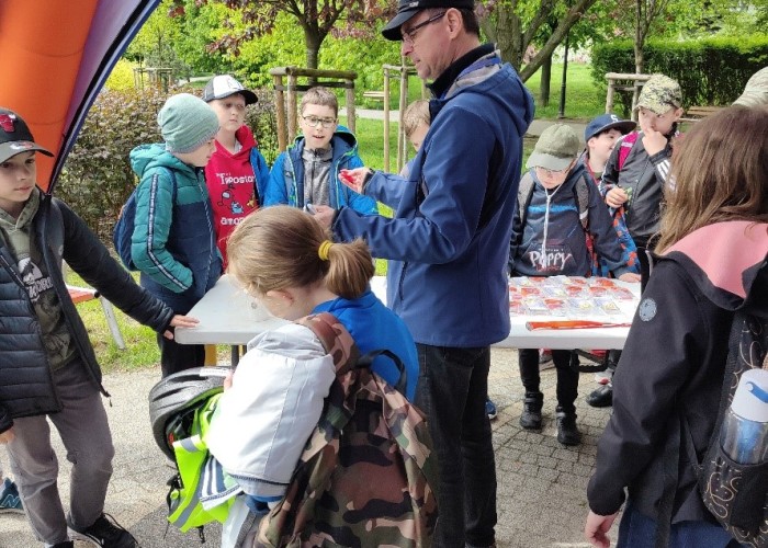 Zdjęcie 2. Uczestnicy „zajęć teoretycznych” z bezpieczeństwa w ruchu drogowym z prowadzącą zajęcia praktyczne Egzaminatorką z WORD w Warszawie Emilią Liberacką na miasteczku rowerowym przy ul. Kazury. (Zdjęcie źródło: WORD w Warszawie)