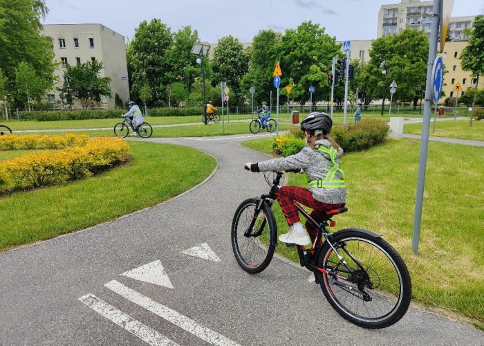 Zdjęcie 6. Dzieci ze szkół podstawowych przygotowujące się do konkursu sprawnościowego z jazdy rowerem po miasteczku rowerowym przy ul. Kazury z Egzaminatorką z WORD w Warszawie Emilią Liberacką. (Zdjęcie źródło: WORD w Warszawie)