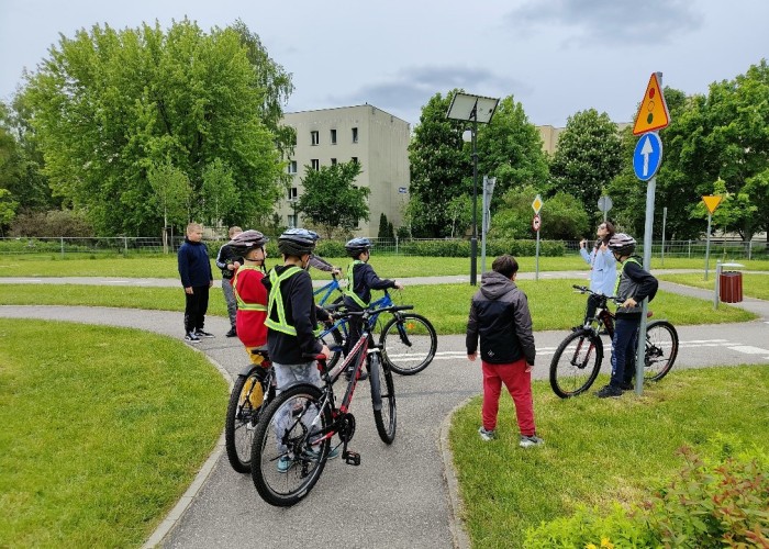 Zdjęcie 7. Dzieci ze szkół podstawowych podczas konkursu sprawnościowego z jazdy rowerem po miasteczku rowerowym przy ul. Kazury z Egzaminatorką z WORD w Warszawie Emilią Liberacką. (Zdjęcie źródło: WORD w Warszawie)