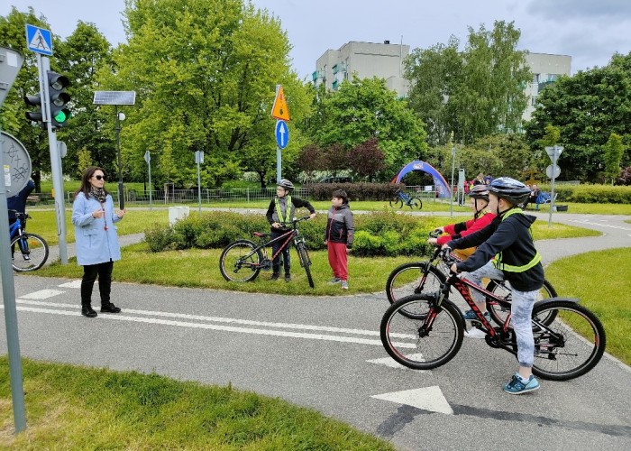 Zdjęcie 8. Dzieci ze szkół podstawowych podczas rozstrzygnięcia konkursu sprawnościowego z jazdy rowerem po miasteczku rowerowym przy ul. Kazury z Egzaminatorami z WORD w Warszawie Emilią Liberacką i Sławomirem Bakalarskim oraz nauczycielami ze szkoły. (Zdjęcie źródło: WORD w Warszawie)