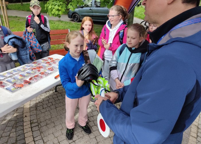 Zdjęcie 10. Wręczanie zestawów BRD uczestnikom zajęć edukacyjnych na miasteczku rowerowym przy ul. Kazury przez Egzaminatora z WORD w Warszawie Sławomira Bakalarskiego. (Zdjęcie źródło: WORD w Warszawie)