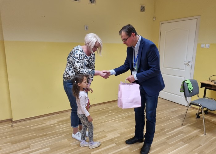 Zdjęcie 7. Wręczenie wychowawczyni w towarzystwie jednej z przedszkolaków ufundowanych przez Urząd Marszałkowski Województwa Mazowieckiego w Warszawie zawieszek odblaskowych. (Zdjęcie źródło: WORD w Warszawie)