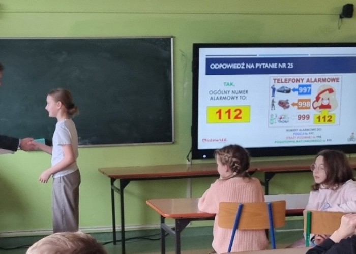 Zdjęcie 11. Wręczenie nagrody wyróżniającej się uczestniczce „konkursu z wiedzy teoretycznej”   przez Egzaminatora z Wojewódzkiego Ośrodka Ruchu Drogowego w Warszawie Sławomira Bakalarskiego (zdjęcie źródło: WORD w Warszawie).