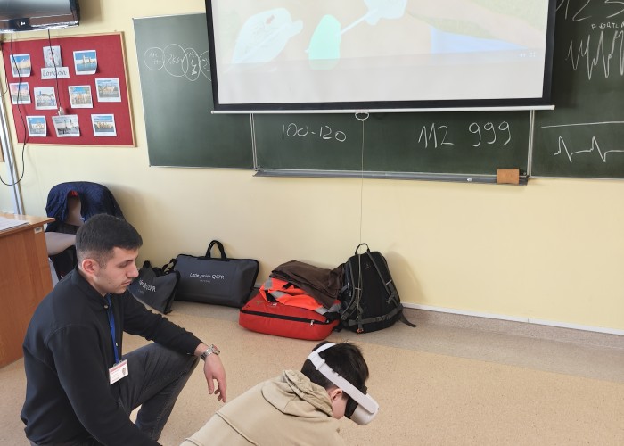 Zdjęcie 10. Uczeń ze SP nr 206 w Warszawie oraz Pan Kacper Wojdalski z Urzędu Marszałkowskiego Województwa Mazowieckiego w Warszawie podczas ćwiczenia za pomocą specjalnych okularów i aplikacji „Virtual Reality” użycia „Defibrylatora” u osoby nieprzytomnej oddychającej w ramach panelu „pierwsza pomoc”. (zdjęcie źródło: WORD w Warszawie).