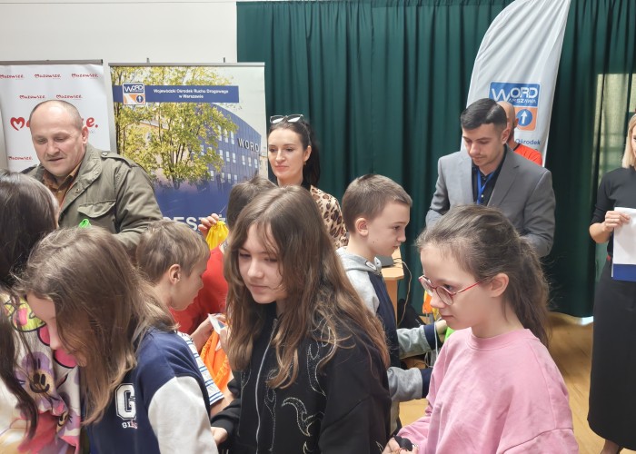 Zdjęcie 4. Wręczenie dzieciom zestawów „BRD”: (od lewej) Pan Leszek Telak – przedstawiciel Wydziału Edukacji i Wychowania z Urzędu Dzielnicy Targówek, Pani Emilia Liberacka Egzaminator z WORD w Warszawie, Pan Kacper Wojdalski – przedstawiciel Urzędu Marszałkowskiego Województwa Mazowieckiego w Warszawie. (zdjęcie źródło: WORD w Warszawie).