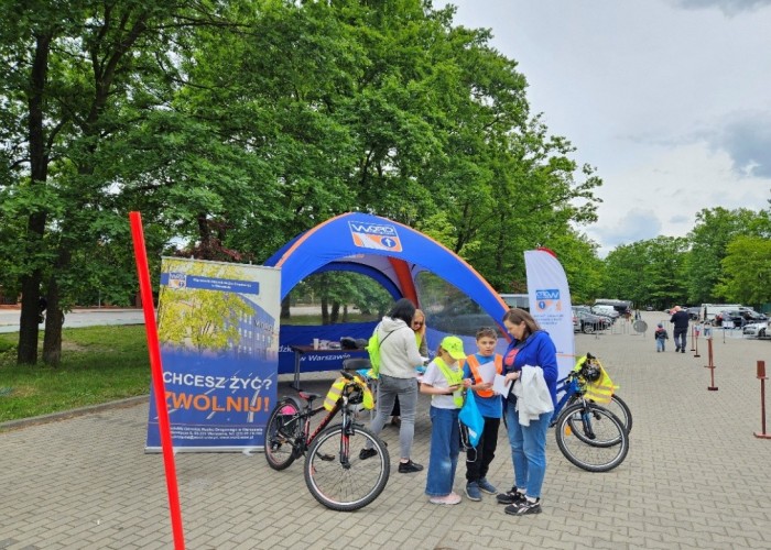 Zdjęcie 2. Uczestnicy pikniku podczas zajęć edukacyjnych dotyczących bezpiecznego uczestnictwa w ruchu drogowym prowadzonych prze Egzaminatora na stanowisku WORD w Warszawie. (zdjęcie źródło: WORD w Warszawie).