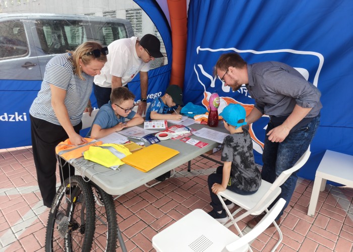Zdjęcie 2. Najmłodsi uczestnicy (wraz z rodzicami) podczas „testu z wiedzy teoretycznej” z przepisów ruchu drogowego na stanowisku WORD w Warszawie (zdjęcie źródło: WORD w Warszawie).