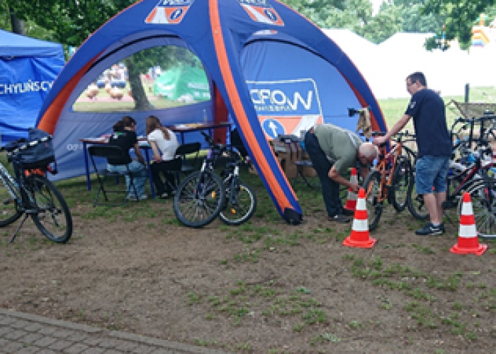 Zdjęcie 6. Uczestniczki „testu z wiedzy teoretycznej” z przepisów ruchu drogowego oraz Pan Leszek Zieliński odpowiedzialny za serwis rowerowy na stanowisku WORD w Warszawie (zdjęcie źródło: WORD w Warszawie). 