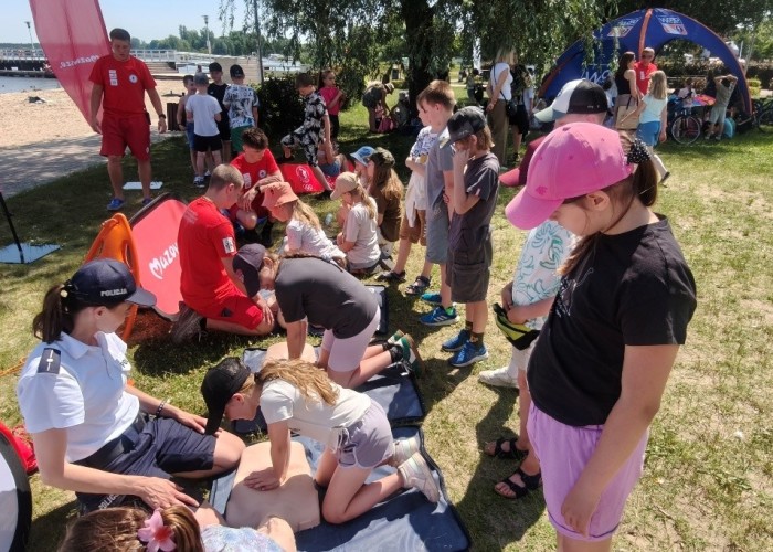 Zdjęcie 2. Dzieci ze szkół podstawowych z Gminy Nieporęt podczas ćwiczeń z udzielania pierwszej pomocy przedmedycznej wraz z Ratownikami z Legionowskiego WOPR i aspirant z Policji Rzecznej w Warszawie - Panią Aleksandrą Wasiak (zdjęcie źródło: WORD w Warszawie).