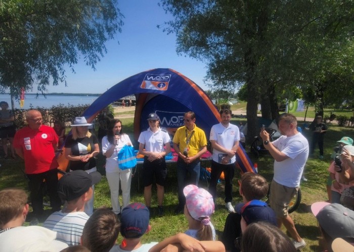 Zdjęcie 7. Na zdjęciu (od lewej): Prezes Legionowskiego WOPR Pan Krzysztof Jaworski, Wójt Gminy Nieporęt – Pani Agnieszka Powała, Członkini Zarządu Województwa Mazowieckiego w Warszawie – Pani Anna Brzezińska, aspirant z Policji Rzecznej w Warszawie - Pani Aleksandra Wasiak, Egzaminator z WORD w Warszawie Pan Sławomir Bakalarski, Mistrz sportów motorowodnych – Pan Bartłomiej Marszałek oraz Kierownik Działu Promocji i Organizacji Wydarzeń Muzeum Sportu i Turystyki  – Pan Piotr Walewski podczas wręczania dzieciom zestawów „BRD”. (zdjęcie źródło: WORD w Warszawie).