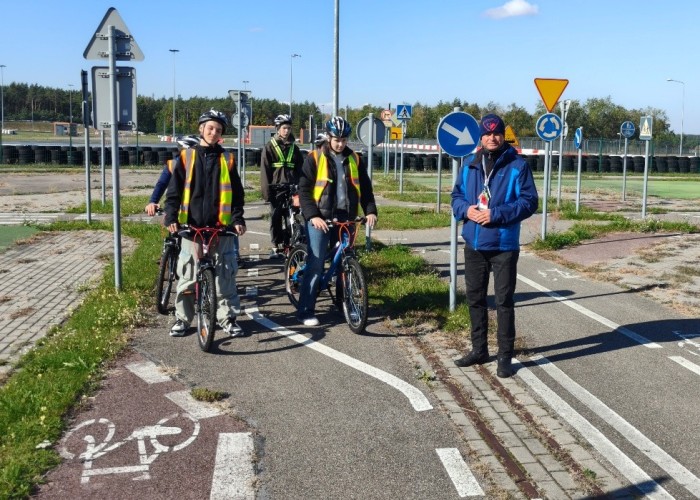 Zdjęcie 1. Uczestnicy „szkolenia praktycznego” na Kartę rowerową na miasteczku rowerowym z prowadzącym zajecia Egzaminatorem z WORD w Warszawie Sławomirem Bakalarskim na miasteczku rowerowym w MCBRD w Modlinie. (Zdjęcie źródło: WORD w Warszawie).