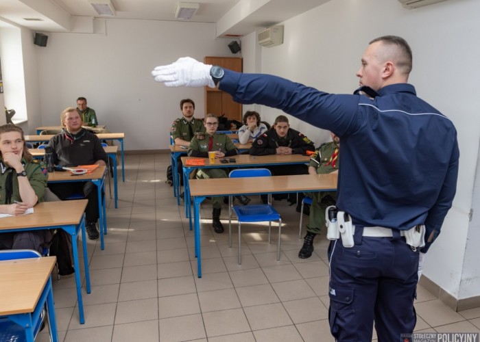 Zdjęcie 2. Na zdjęciu: uczestnicy części teoretycznej szkolenia z kierowania ruchem drogowym - Harcerze Chorągwi Stołecznej Związku Harcerstwa Polskiego oraz sierżant Patryk Cieśliński Policjant z WRD Komendy Stołecznej Policji (Zdjęcie źródło: Marek Szałajski - Komenda Stołeczka Policji).